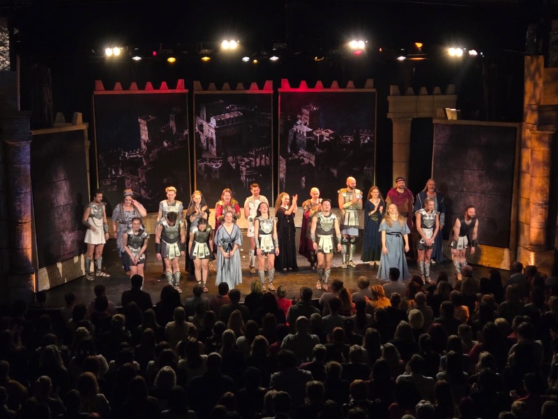 Na jevišti stojí všichni účinkující, zatímco publikum tleská ve stoje.