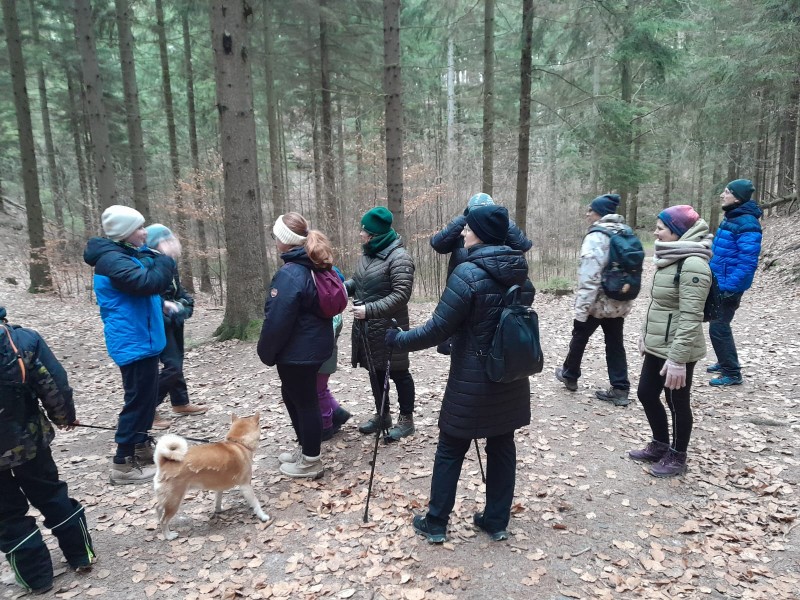 Skupinka čeká v zimním lese na další účastníky pochodu.