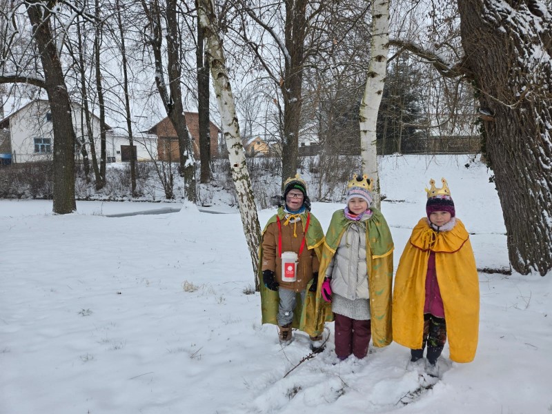 Tři králové stojí v zasněžené krajině.