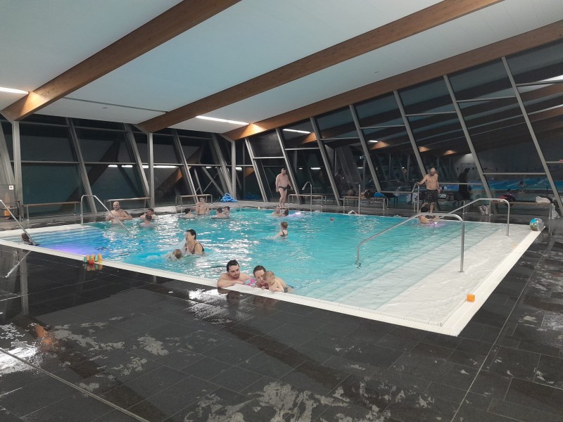 Rodinný bazén plný dětí a rodičů, kteří si společně hrají ve vodě..